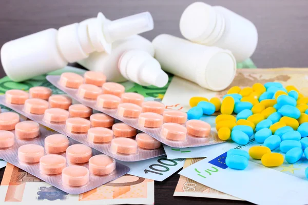 Prescription drugs on money background representing rising health care costs. On wooden background — Stock Photo, Image