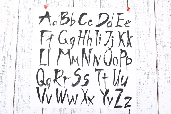 Aquarelas alfabeto no fundo de madeira — Fotografia de Stock