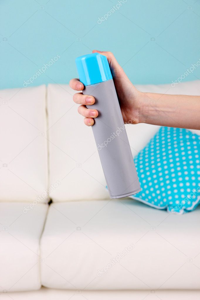 Sprayed air freshener in hand on home interior background Stock Photo