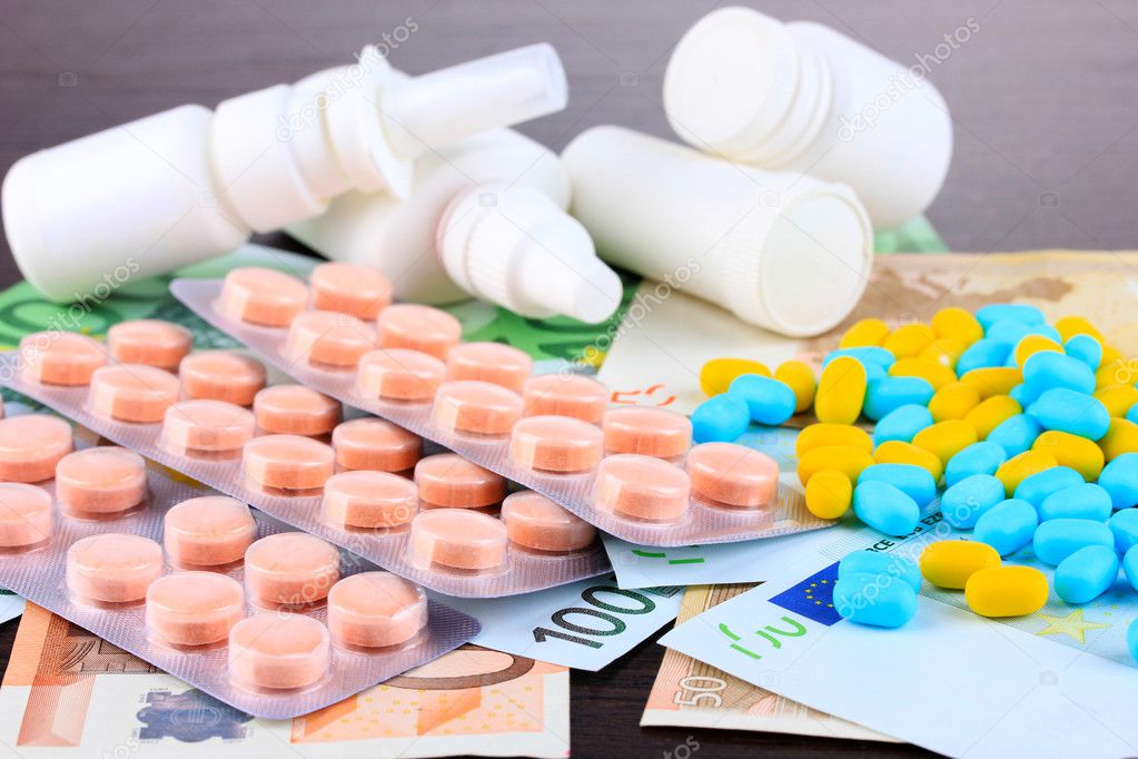 Prescription drugs on money background representing rising health care costs. On wooden background