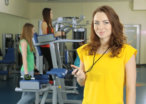 Treinador jovem e mulheres envolvidas em simulador no ginásio — Fotografia de Stock
