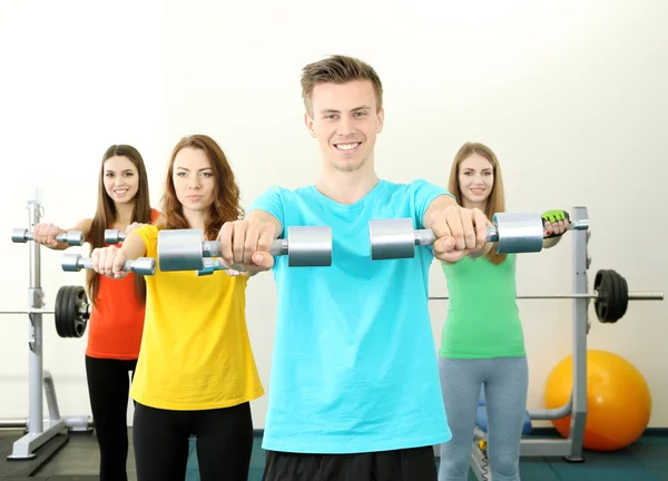 Jóvenes hermosas personas comprometidas con pesas en el gimnasio — Foto de Stock