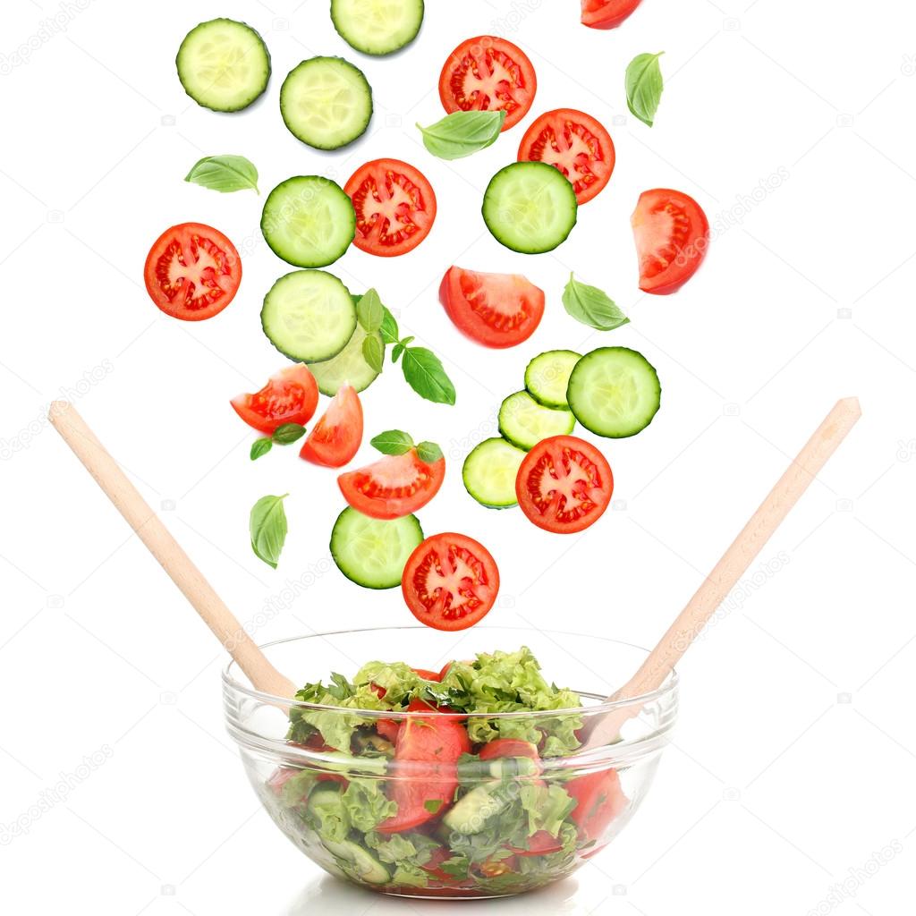 Fresh mixed vegetables falling into bowl of salad isolated on white