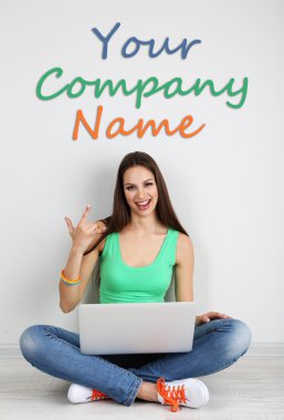 Odada dizüstü bilgisayar ile oturup güzel bir genç kadın