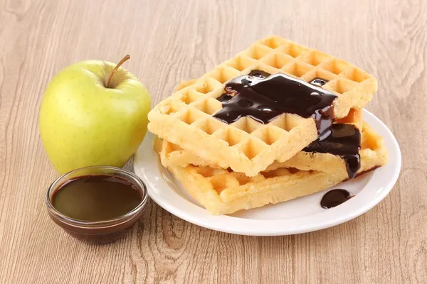 Waffles saborosos com chocolate na placa no fundo de madeira — Fotografia de Stock