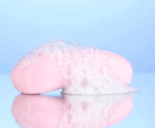 Sapone rosa con schiuma su sfondo blu — Foto Stock