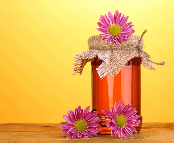 Sweet honey in jar on wooden table on yellow background — Stock Photo, Image