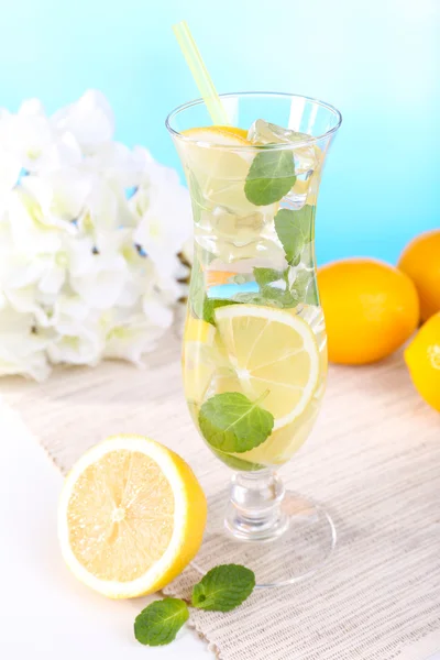 Стакан коктейля с лимоном и мятой на столе на светло-голубом фоне — стоковое фото