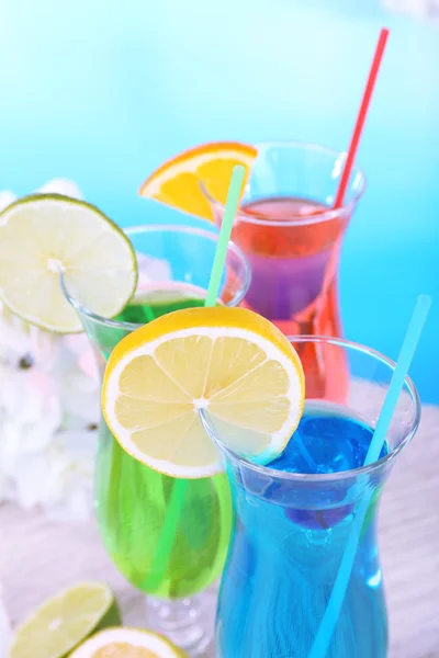 Glasses of cocktails on table on light blue background — Stock Photo, Image