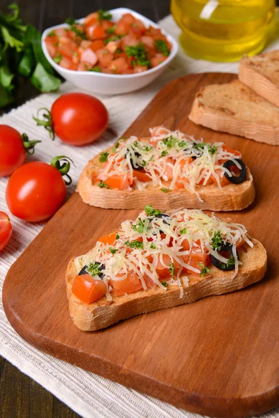 Delicious bruschetta with tomatoes on cutting board close-up — Stock Photo, Image