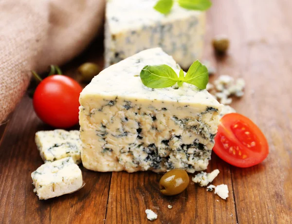Sabroso queso azul con tomate, aceitunas y albahaca, sobre mesa de madera — Foto de Stock