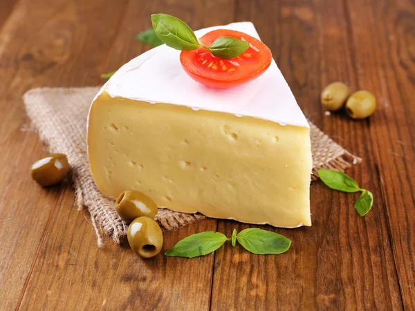 Smakelijke camembert kaas met tomaat, basilicum en olijven, op houten tafel — Stockfoto