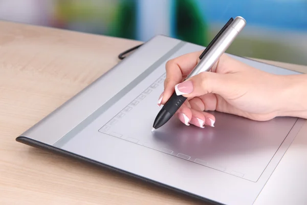 Female hand using graphics tablet on table on bright background — Stock Photo, Image