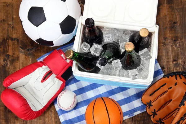 Ice chest full of drinks in bottles on color napkin, on wooden background — Stock Photo, Image