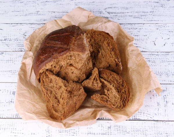 Pieces of bread on paper on wooden background — Stock Photo, Image