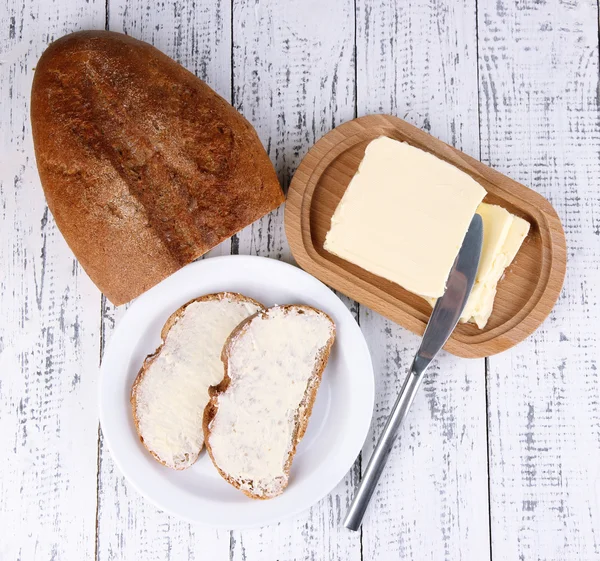 Pain de seigle avec beurre sur planche à découper sur fond bois — Photo