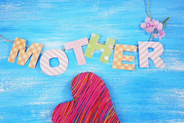 Mother- lettering of handmade paper letters on blue wooden background