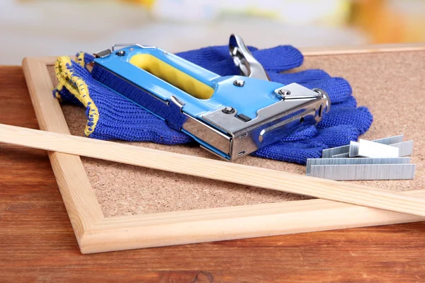 Grampeador de construção com luvas e grampos na placa de cortiça de perto — Fotografia de Stock