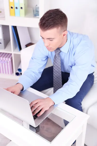 Jovem bonito trabalhando no laptop em casa — Fotografia de Stock