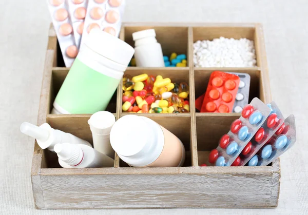 Medical pills, ampules in wooden box, on color background — Stock Photo, Image