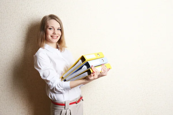 Portrait of businesswoman with folders near wall — Stock Photo, Image