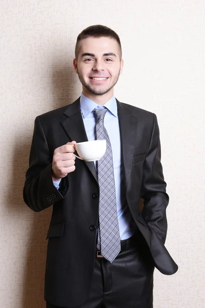 Retrato de homem de negócios com xícara de café perto da parede — Fotografia de Stock