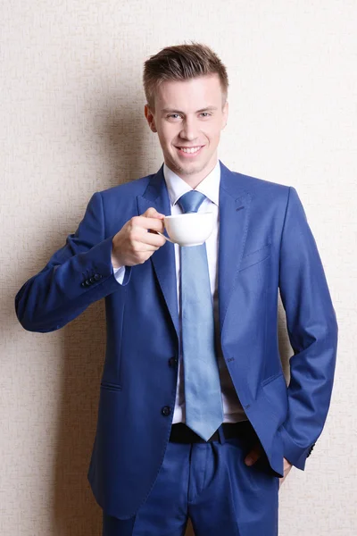 Portret van zakenman met kop koffie in de buurt van muur — Stockfoto