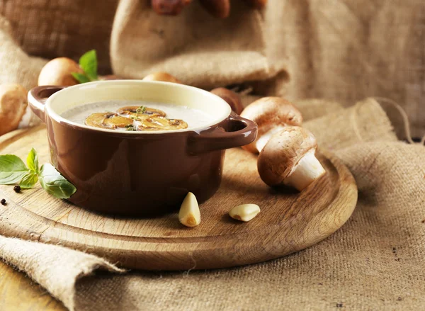 Composition with mushroom soup in pot, fresh and dried mushrooms, on wooden table, on sackcloth background — Stock Image Composition with mushroom soup in pot, fresh and dried mushrooms, on wooden table, on sackcloth background Stock Photo