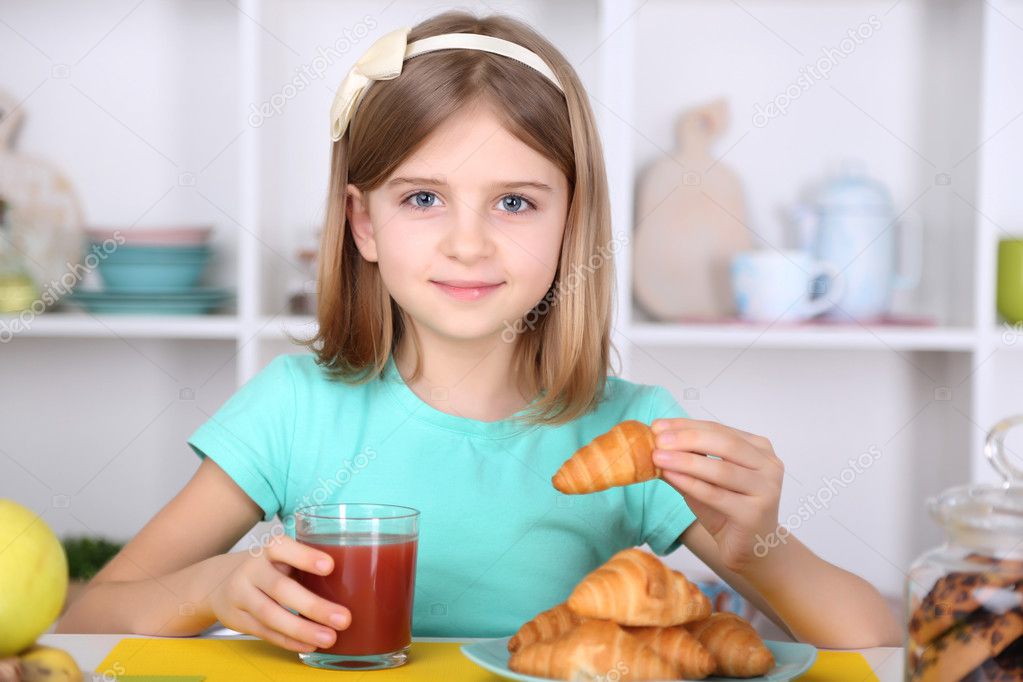 Beautiful little girl eating breakfast in kitchen at home — Stock Photo