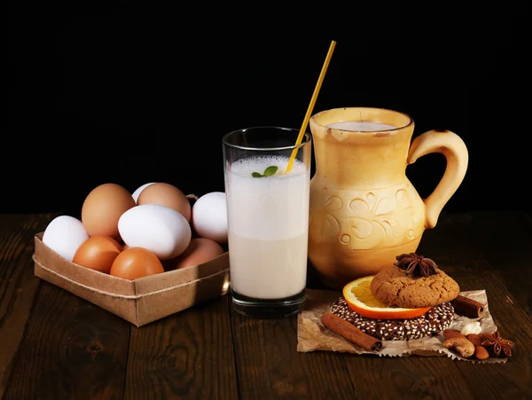 Ajerkoniak z mlekiem i jajami na stół i czarne tło — Zdjęcie stockowe