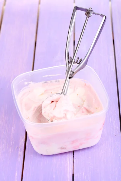 Helado en recipiente y cuchara de helado en mesa de madera de primer plano — Foto de Stock