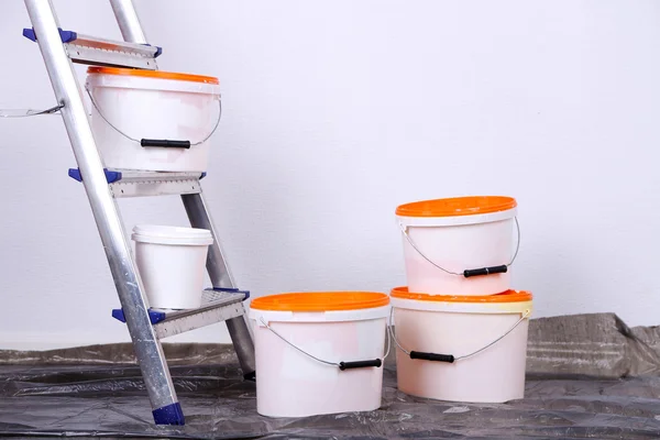 Cubos con pintura y escalera sobre fondo de pared. Foto conceptual de los trabajos de reparación en la habitación — Foto de Stock