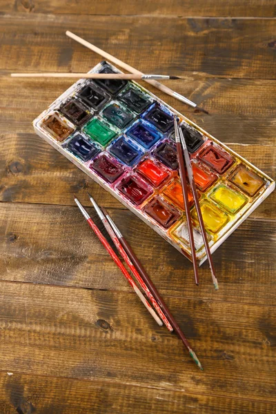 Colourful watercolors and brushes on wooden background — Stock Photo, Image