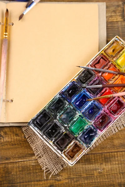 Composizione con acquerelli colorati, pennelli e bozzetto su fondo in legno — Foto Stock