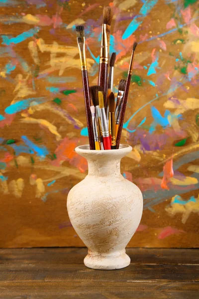 Štětce v váza na dřevěné pozadí — Stock fotografie