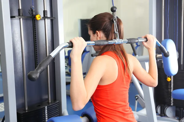 Mujer joven entrenando con pesas en el gimnasio — Foto de Stock