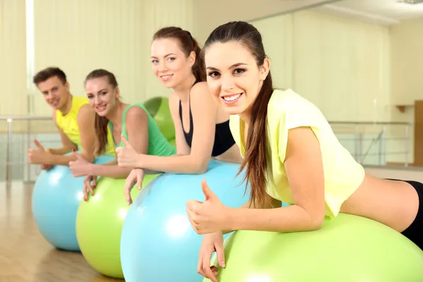 Группа молодых людей тренируется с гимнастическим мячом в тренажерном зале — стоковое фото