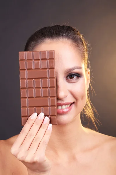 Porträtt av vacker ung flicka med choklad på brun bakgrund — Stockfoto