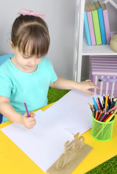 Petite fille dessine assis à table dans la chambre — Photo