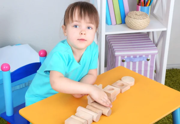Bambina gioca con blocchi di costruzione seduti a tavola in camera — Foto Stock