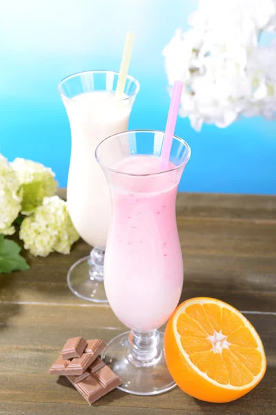 Milk shakes with fruits on table on light blue background — Stock Photo, Image