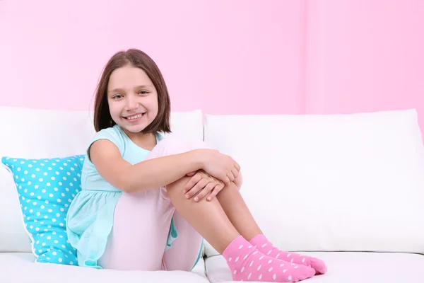 Hermosa niña sentada en el sofá, en el fondo interior de casa —  Fotos de Stock