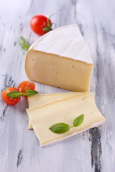 Schmackhafter Camembert-Käse mit Tomate und Basilikum, auf Holztisch — Stockfoto