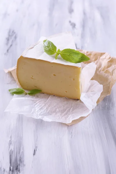 Tasty Camembert cheese with basil, on wooden table — Stock Photo, Image