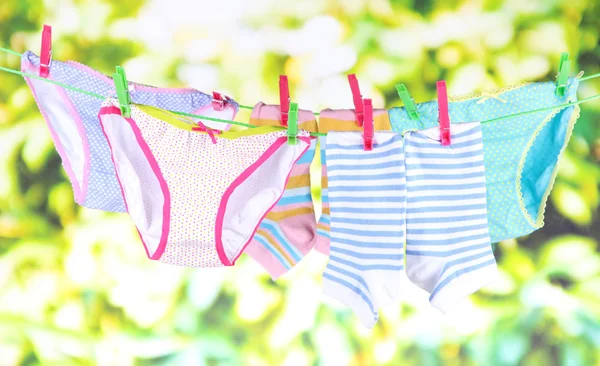 Baby clothes hanging on clothesline, on bright background — Stock Photo, Image