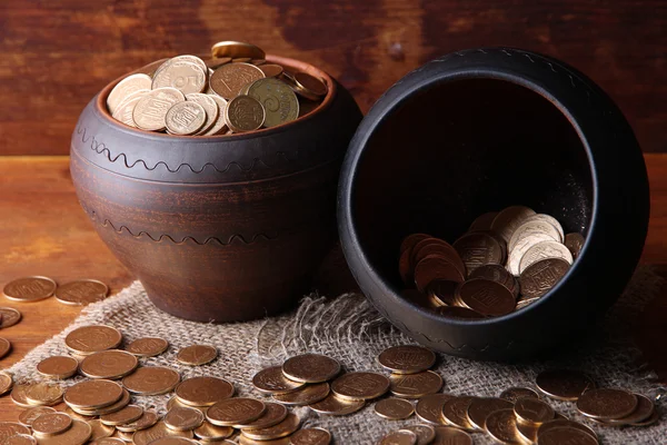 Gouden munten in keramische potten, op houten achtergrond — Stockfoto