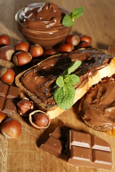 Pane con cioccolato dolce alla nocciola spalmato su fondo di legno — Foto Stock