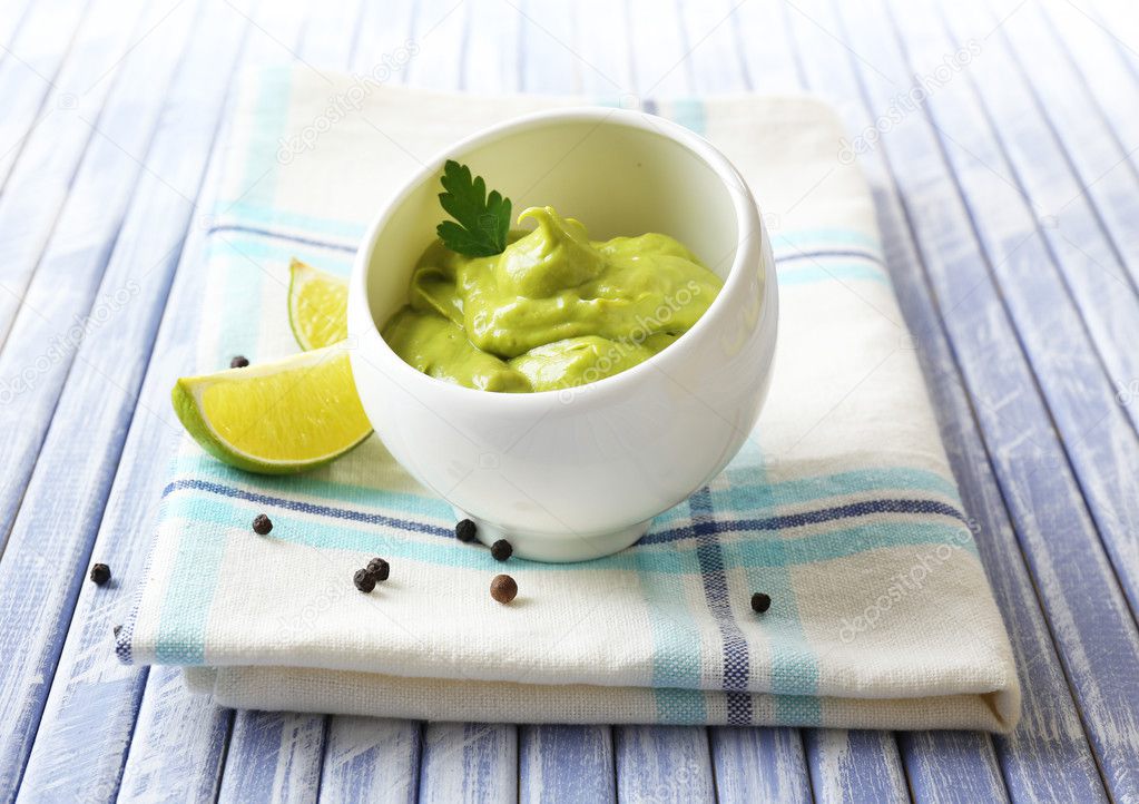 Fresh guacamole in bowl on wooden table