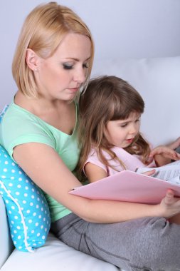sevimli küçük kız anne üzerinde gri arka koltukta ile kitap okuma