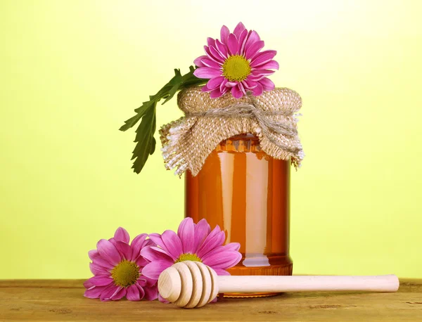 Drizzler 緑色の背景で木製のテーブルの上の瓶に甘い蜂蜜 — ストック写真